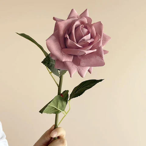 A mauve artificial rose with a single bloom and green leaves