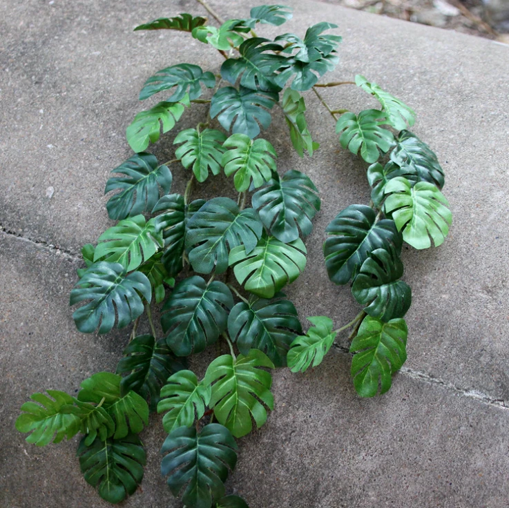 Artificial split green leaves along trailing vines arranged on a stone floor