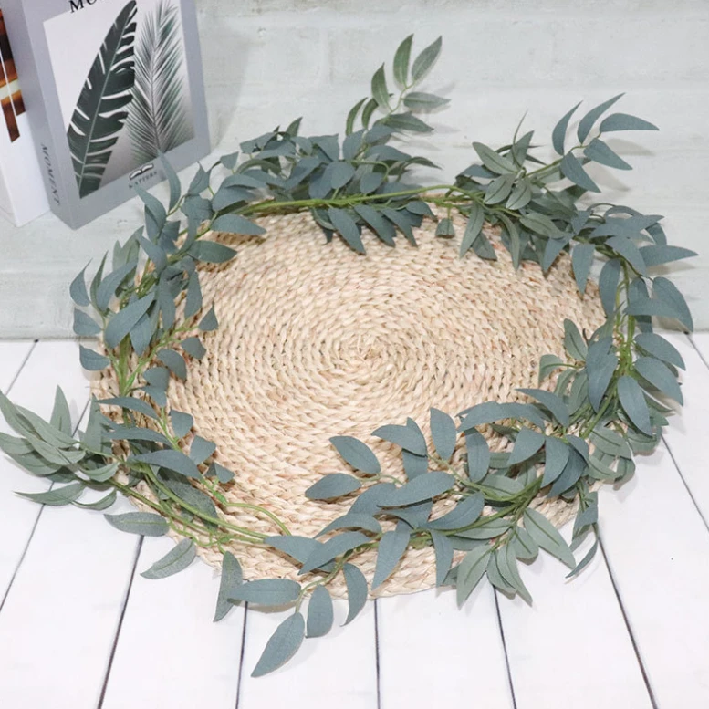 Grey-green artificial leaf garland arranged around a woven circular mat