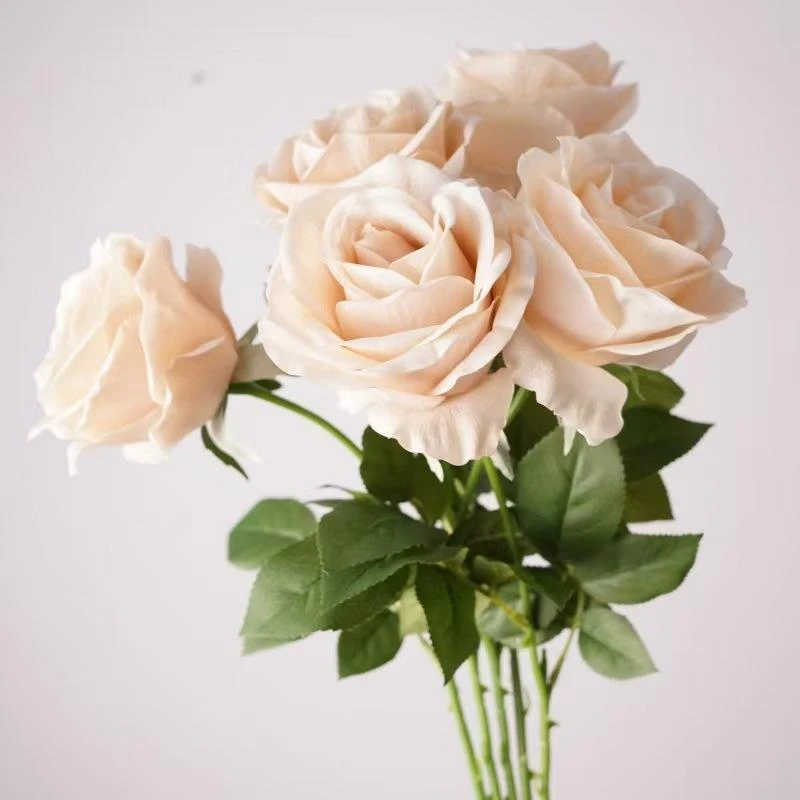 Cream artificial roses grouped together with green leaves