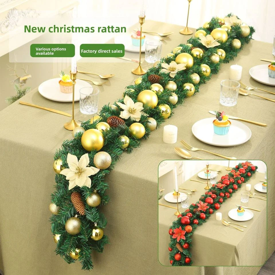 Artificial green Christmas garland with pale flowers and gold decorations arranged along a table