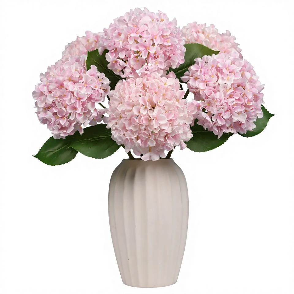 Pale pink artificial hydrangea stems with textured petals in a tall cream vase