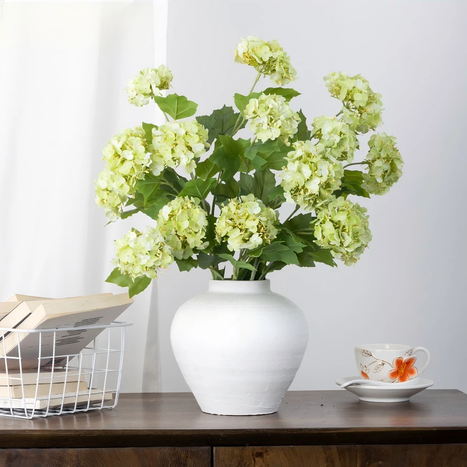 White and green artificial hydrangeas styled in a white vase