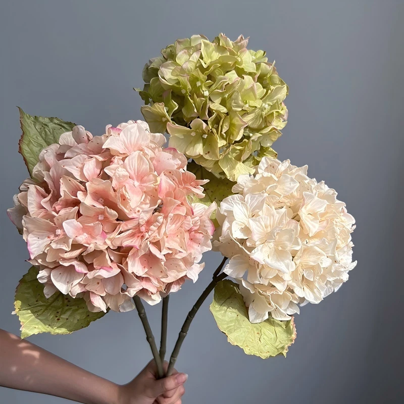Pink, cream and green artificial hydrangea stems held as a group