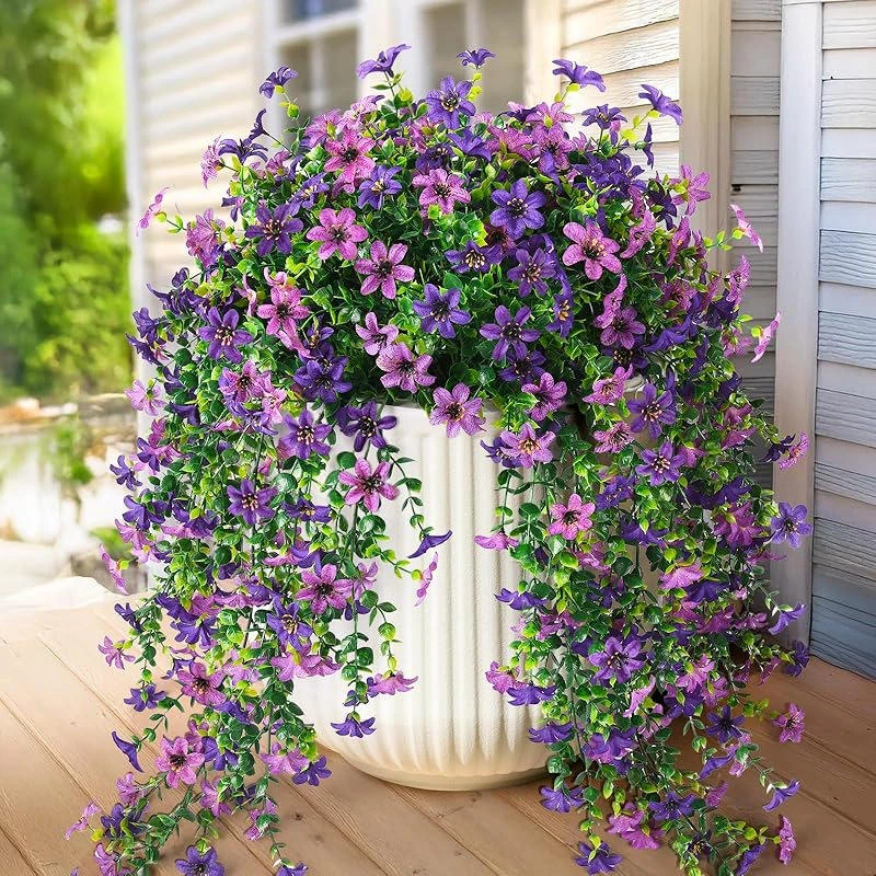 Purple and white artificial flowers with trailing greenery in a hanging display