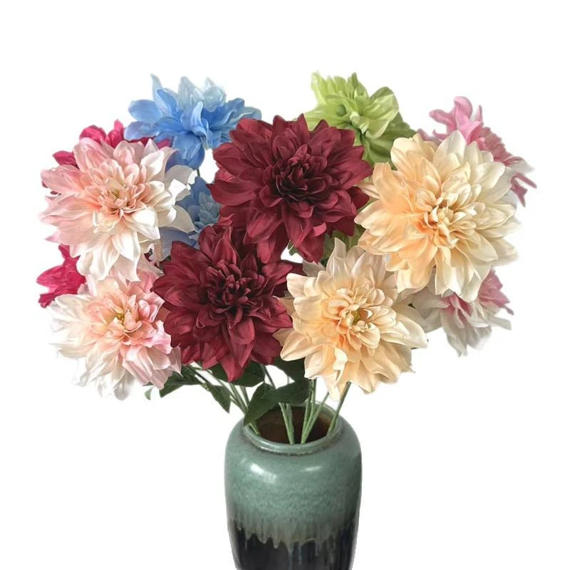 Cream, pink, burgundy and peach artificial dahlia-style flowers grouped in a green vase